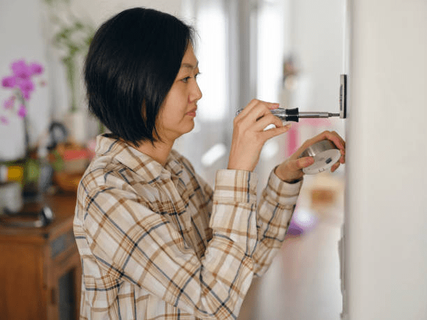 Woman installing a smart thermostat in a home