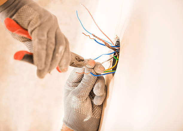 worker installing electrical wires man in glovers using pliers working with electrical wires in wall